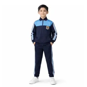 Boy in navy school tracksuit uniform with sky-blue shoulder panels and side stripes, full-zip jacket and track pants
