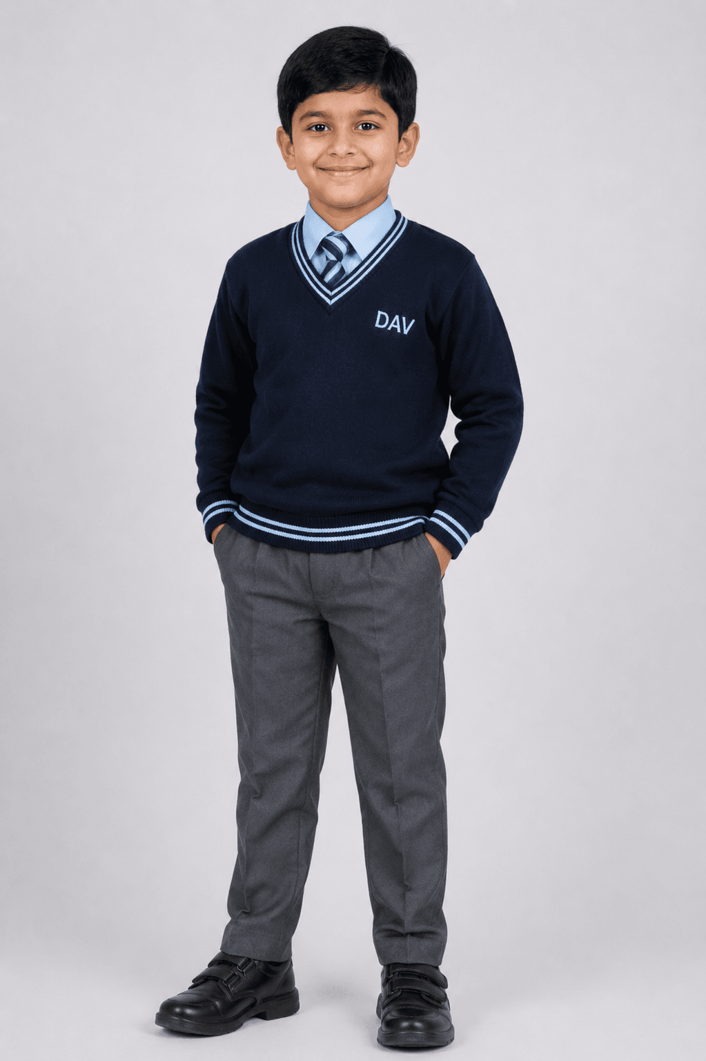 Studio side pose of Indian school boy wearing navy blue DAV full sleeve winter sweater with grey school pants