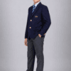 Side angle studio photo of Indian boy wearing navy blue DAV school blazer with tie and grey school trousers
