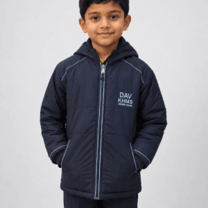 Close-up front view of Indian child wearing navy blue DAV KHMS winter school jacket with hood and zipper on grey studio background