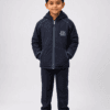 Full body studio photo of Indian boy wearing DAV navy blue padded winter school jacket with formal school trousers and shoes