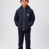 Full body studio photo of Indian boy wearing DAV navy blue padded winter school jacket with formal school trousers and shoes