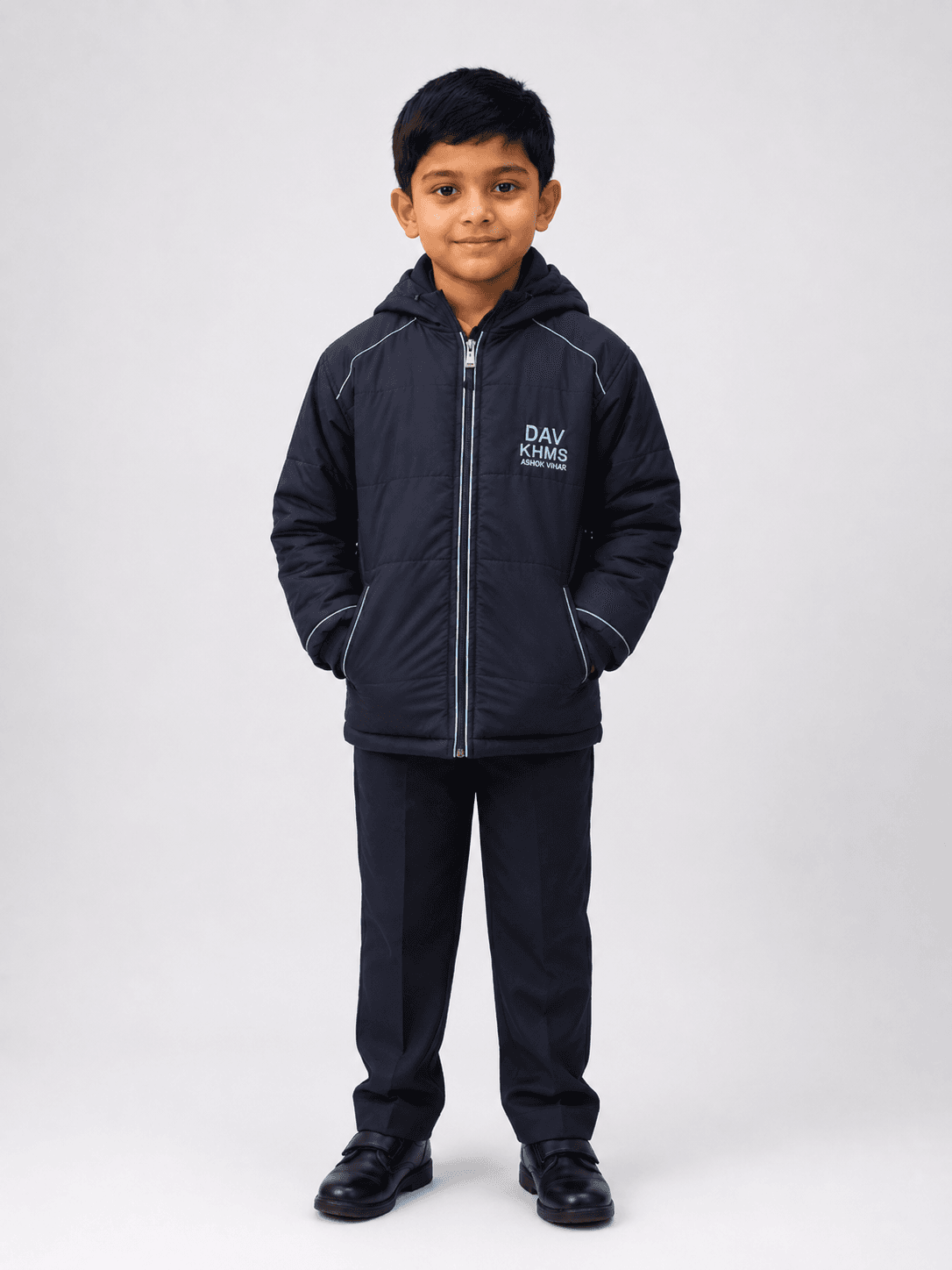Full body studio photo of Indian boy wearing DAV navy blue padded winter school jacket with formal school trousers and shoes